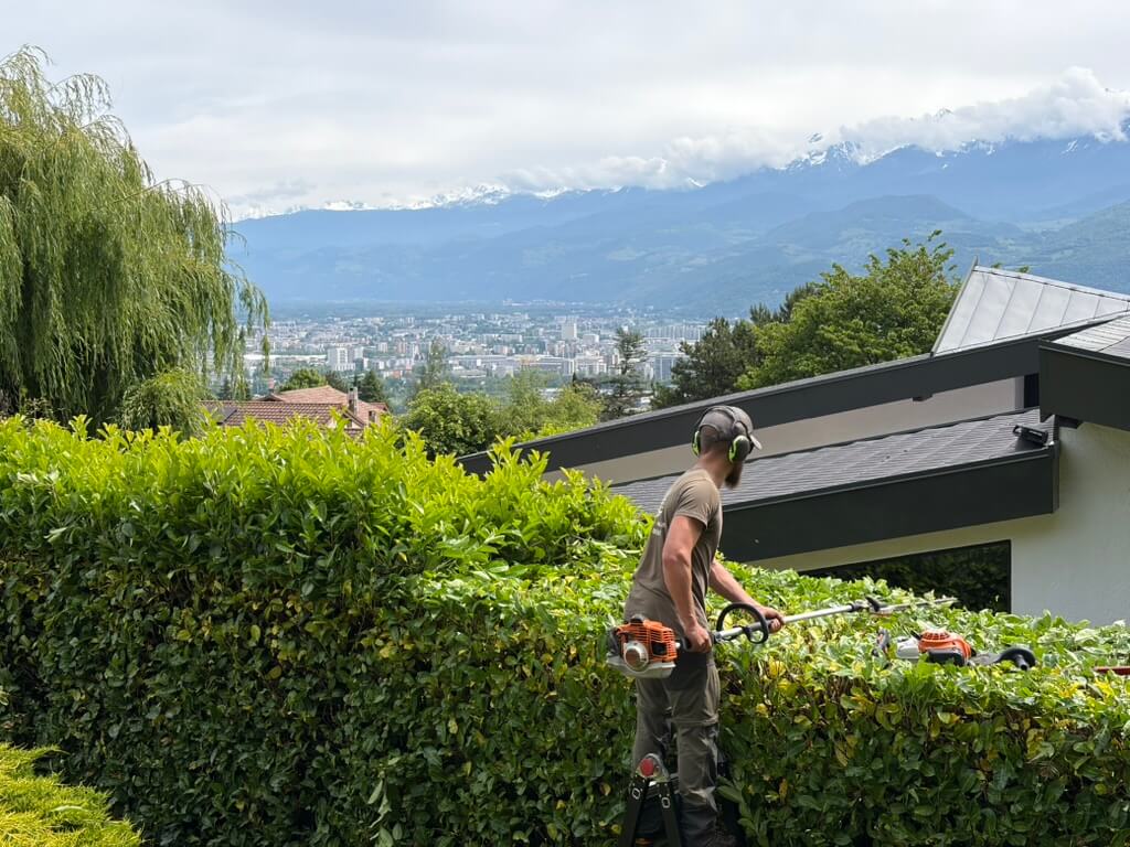 Paysagiste à Crolles taillant une haie avec vue sur la vallée