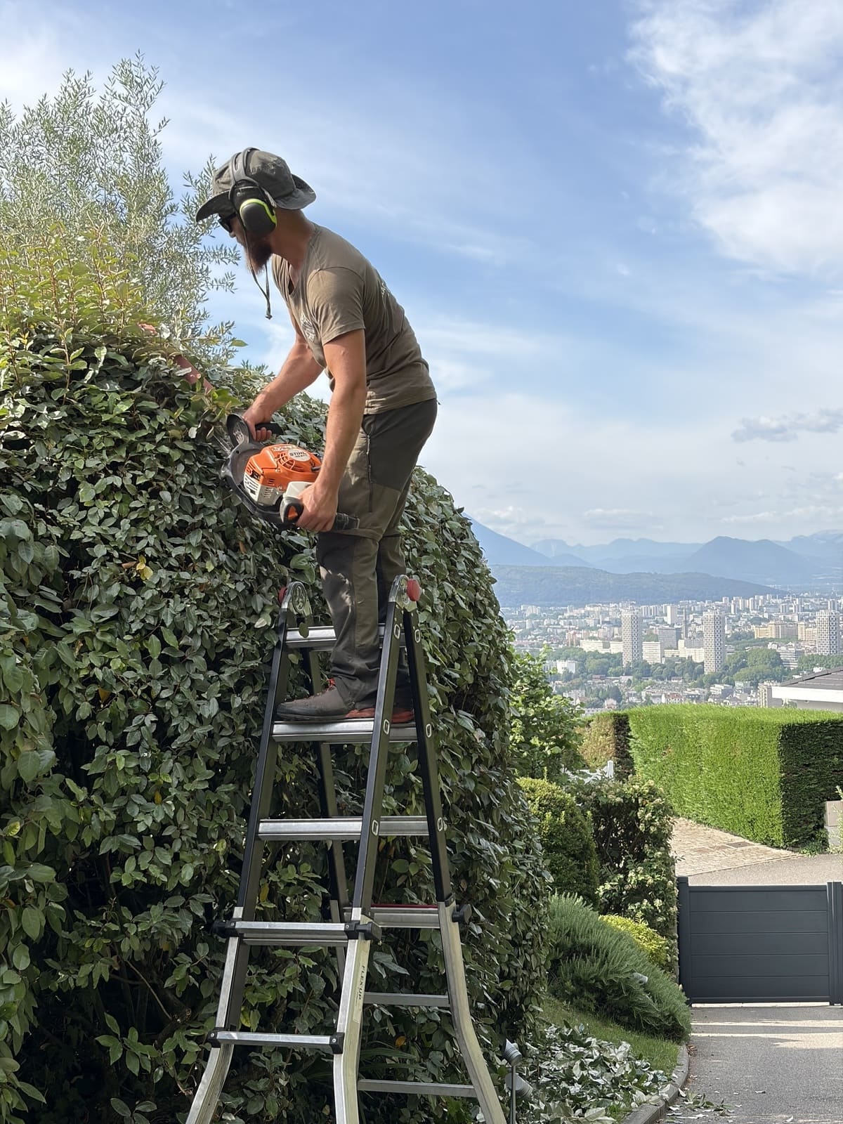 Paysagiste à Crolles taillant une haie avec vue sur la vallée